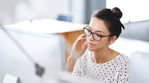 Woman at computer, wearing glasses and looking for new jobs