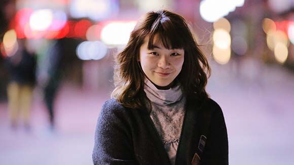 Female professional smiling at camera, outside with blurry street view behind 