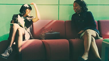 Two women sitting on red couch discussing their interview techniques