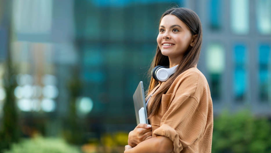 Happy pretty lady student posing at university campus, holding g