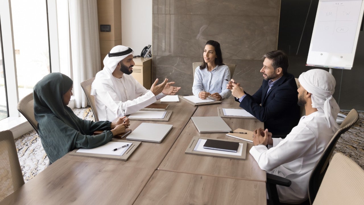 Arab and Hispanic business leaders discussing project strategy, company management, talking at large meeting table. Board of directors, stakeholders meeting banner shot