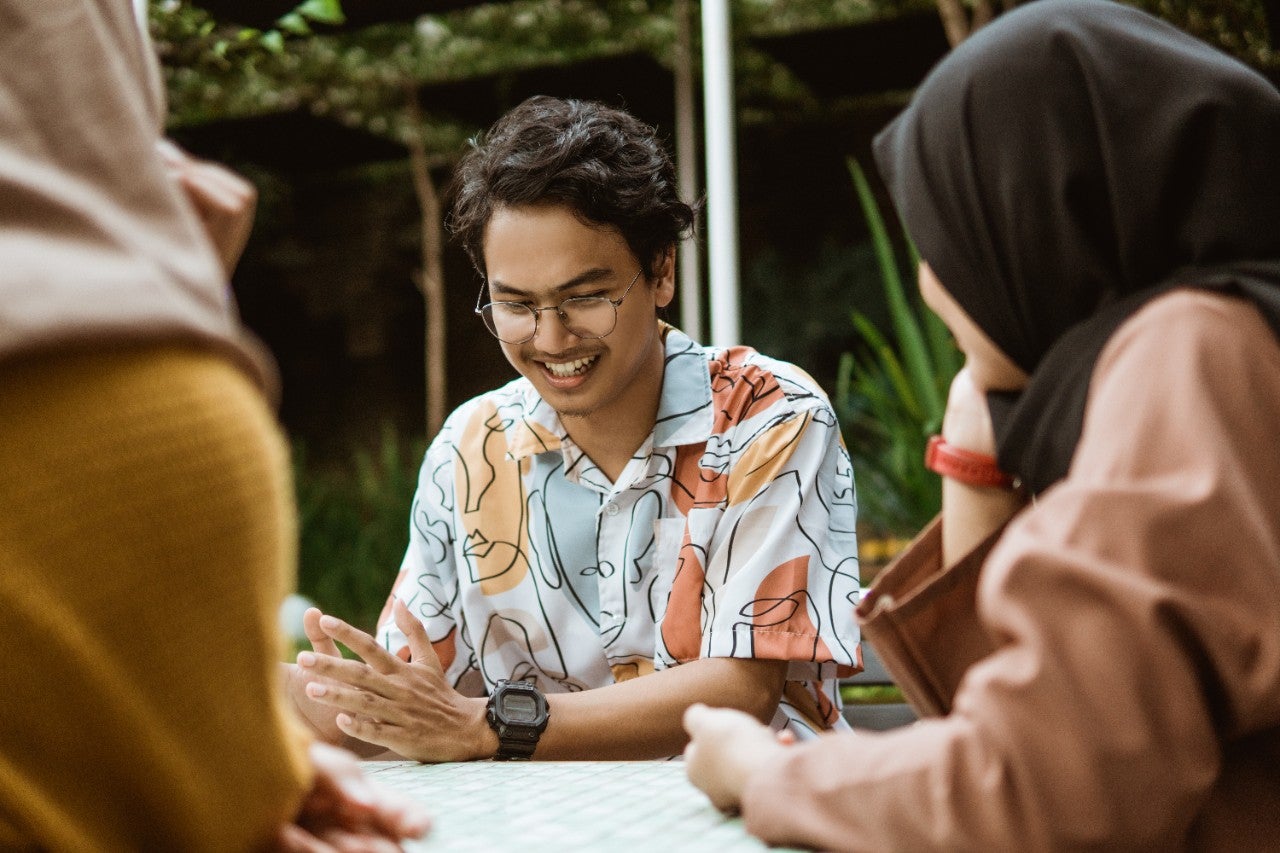male students smile chatting while hanging out with friends in the coffee shop
