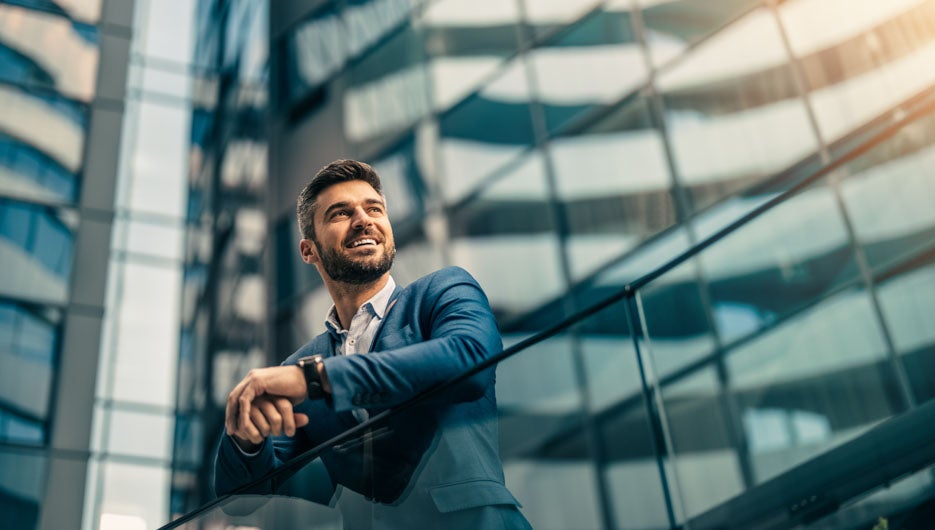 Handsome confident businessman portrait in front of modern buildings.